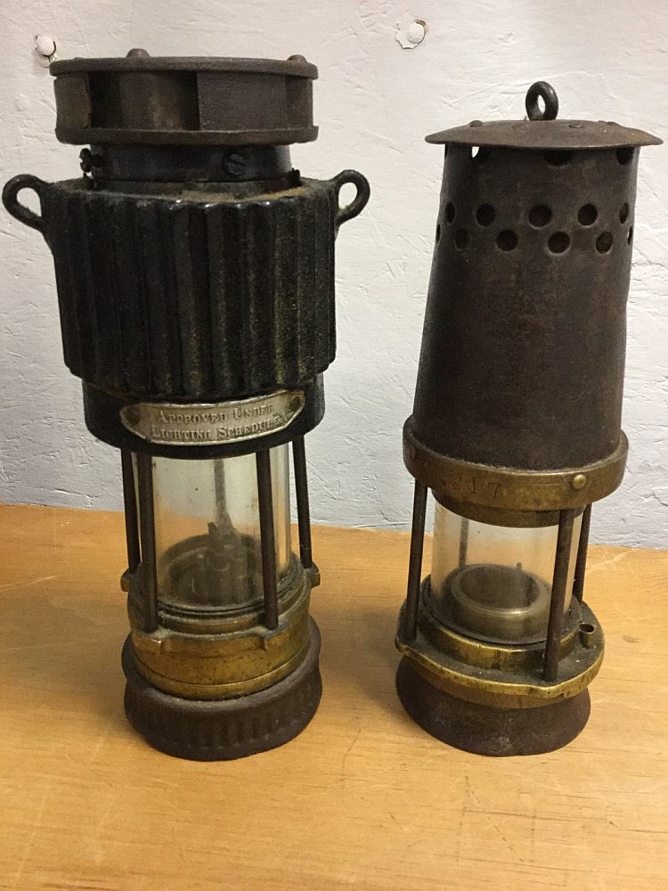 A brass miners lamp with fluted cover having tubular glass enclosure