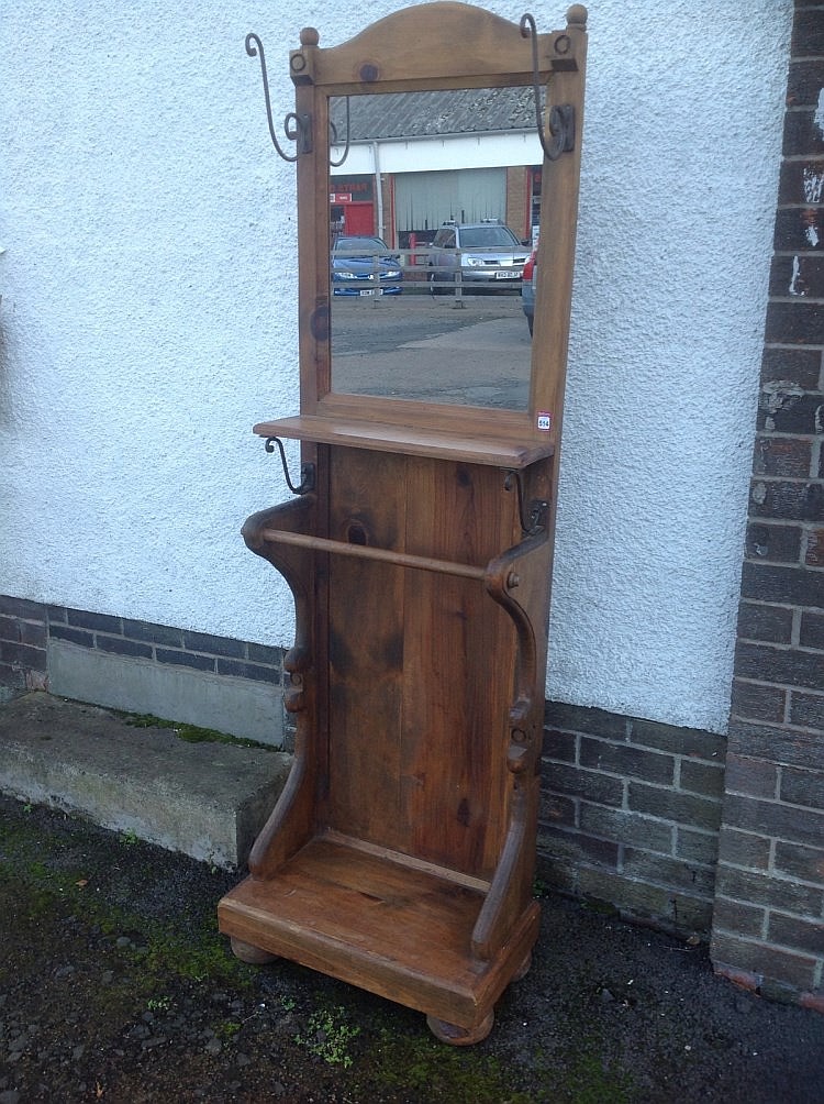 A pine hallstand, the mirror in frame mounted with scrolled pegs above