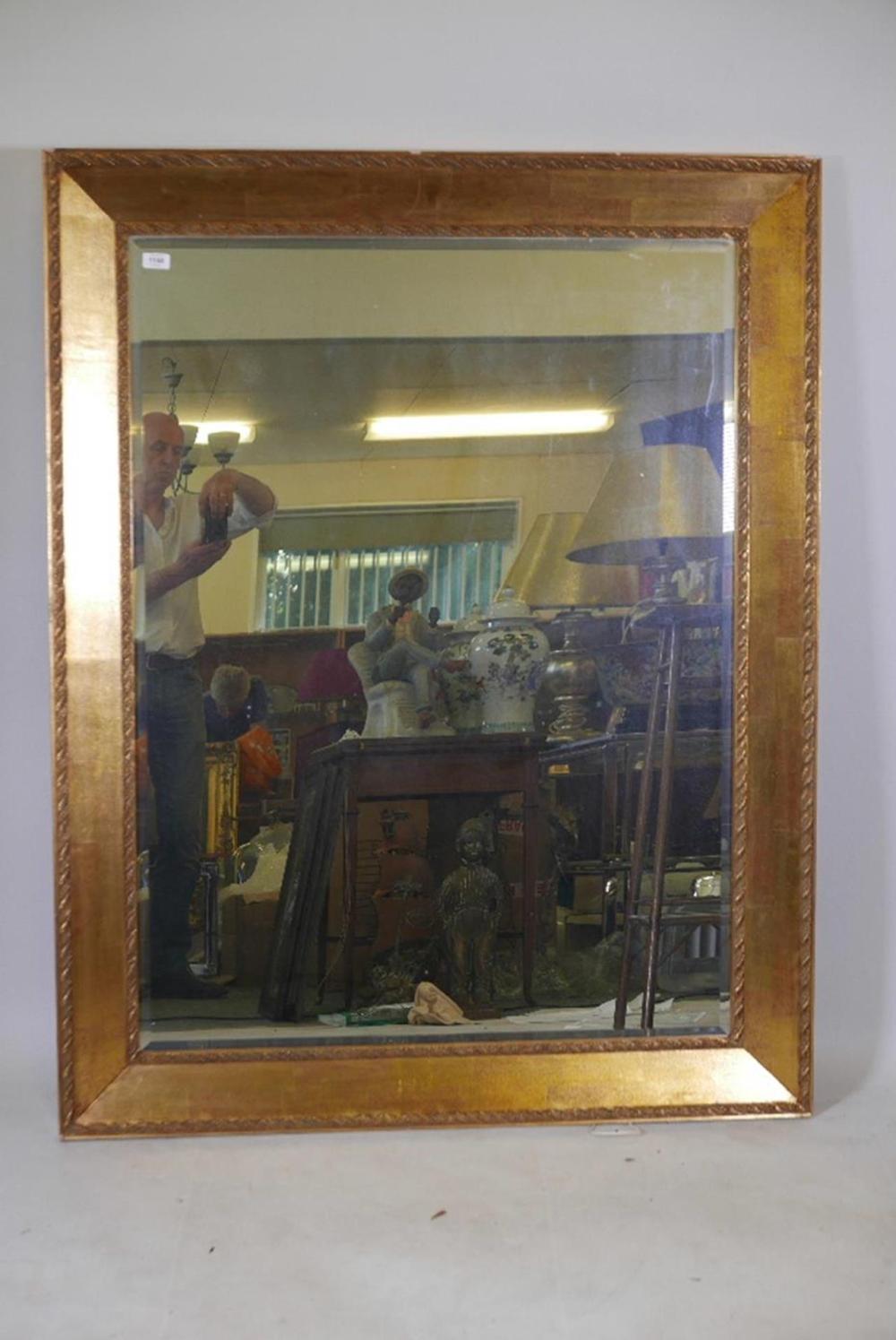 A LARGE GILT FRAMED BEVELLED GLASS WALL MIRROR WITH ACANTHUS LEAF MOULDED FRAME