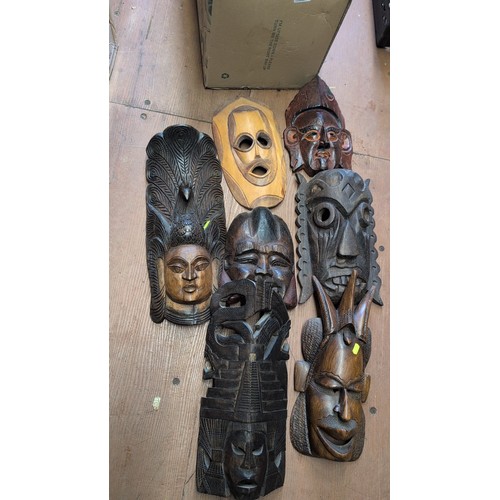 A group of carved wooden masks and figural wall plaques.